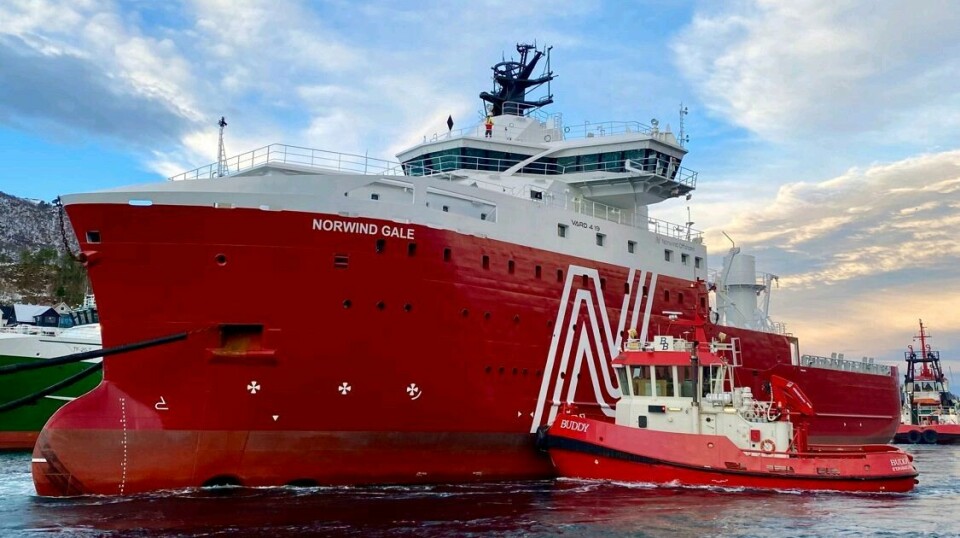 Det røde og hvit havvindskipet Norwind Gale blir hjulpet til kai av en liten slepebåt ved Vard Brattvaag