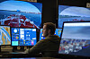 Person sitter foran flere skjermer i maritim skipsnavigasjonssimulator.