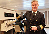 En uniformert sjøoffiser står ved siden av en iskremmaskin inne i et skipsinnredet rom.