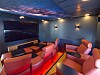 Moderne lounge med rosa stoler, svart skjerm, dempet belysning og tak dekorert som en stjernehimmel.