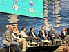 En panelgruppe sitter på en scene foran en turkis presentasjonsskjerm.