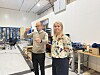 To personer i et lyst laboratorium med teknisk utstyr og arbeidsbenker.